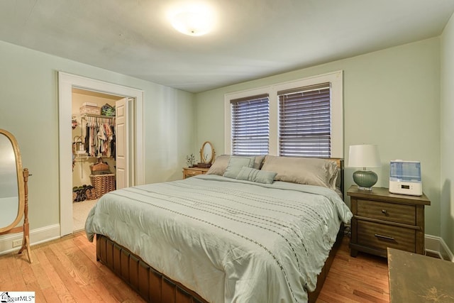 bedroom with a spacious closet, a closet, and light hardwood / wood-style floors