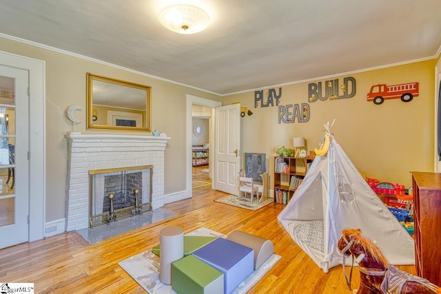 playroom with a fireplace, crown molding, and hardwood / wood-style floors