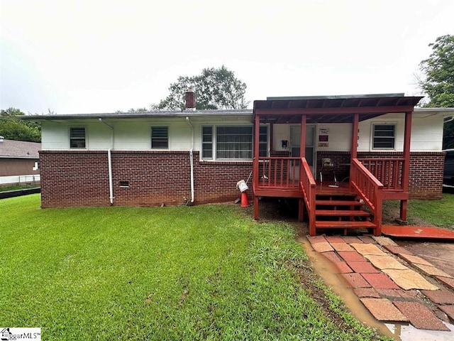 rear view of house featuring a lawn and brick siding