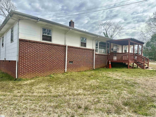 rear view of house featuring brick siding, a chimney, and a yard