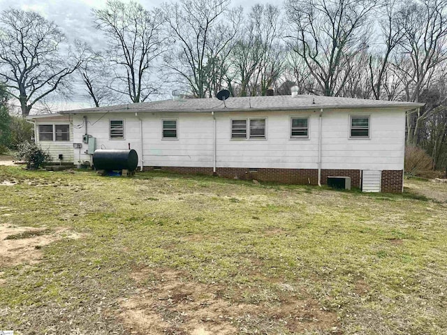 rear view of property with a yard, crawl space, and heating fuel