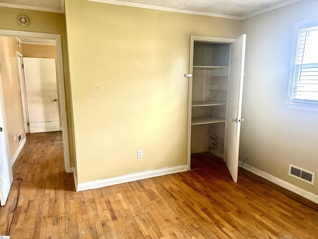 unfurnished bedroom with visible vents, crown molding, light wood-style flooring, and baseboards