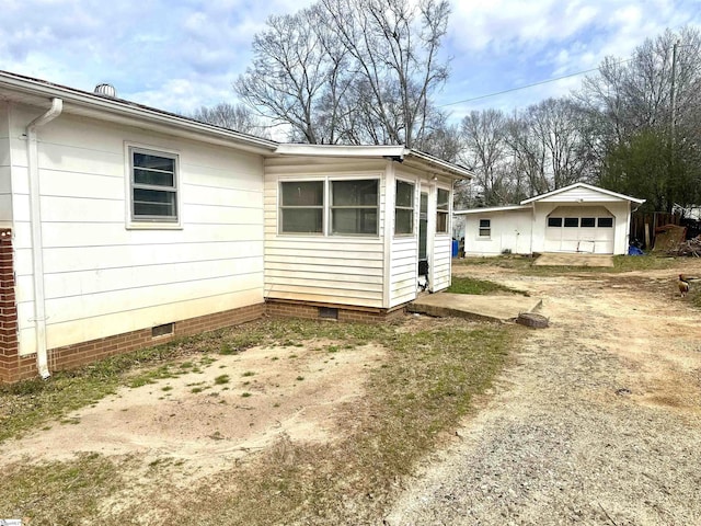 view of side of property with driveway, crawl space, and a detached garage