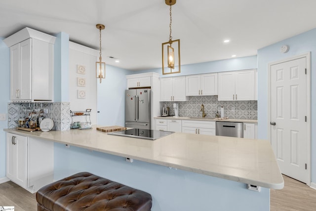 kitchen featuring kitchen peninsula, decorative light fixtures, stainless steel appliances, and white cabinets