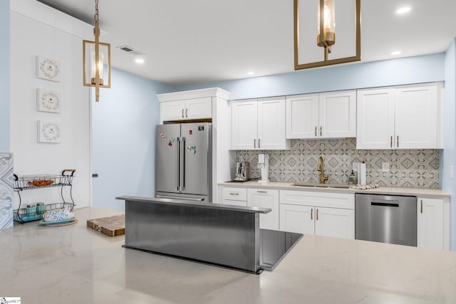 kitchen featuring sink, hanging light fixtures, stainless steel appliances, backsplash, and white cabinets