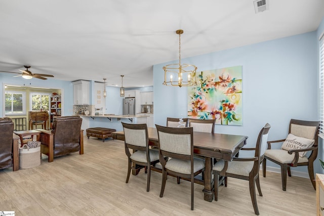 dining space featuring ceiling fan with notable chandelier and light wood-type flooring