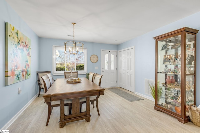 dining space with light wood-type flooring and a chandelier