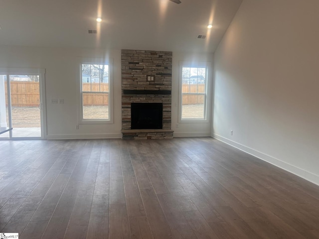 unfurnished living room with a fireplace, visible vents, dark wood-style floors, and baseboards