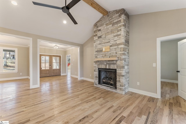 unfurnished living room with light wood-style floors, ceiling fan, a stone fireplace, beamed ceiling, and baseboards