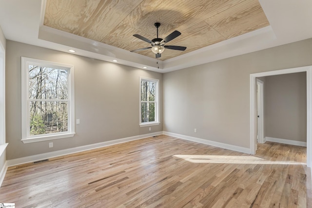 unfurnished room featuring wood ceiling, a tray ceiling, and baseboards