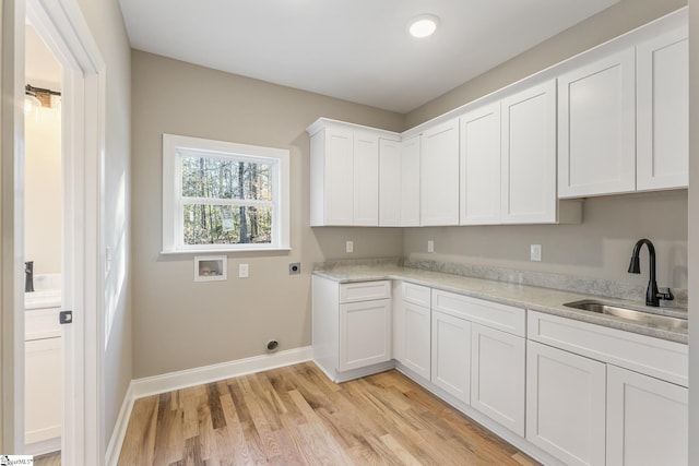 laundry room featuring hookup for a washing machine, hookup for an electric dryer, a sink, light wood-style floors, and cabinet space