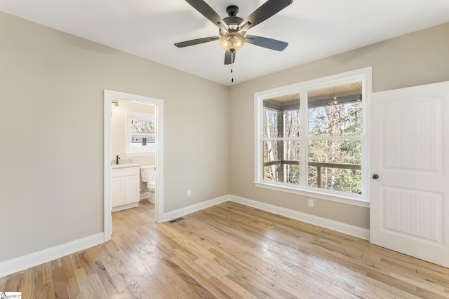 unfurnished bedroom with visible vents, baseboards, a ceiling fan, light wood-style flooring, and ensuite bathroom