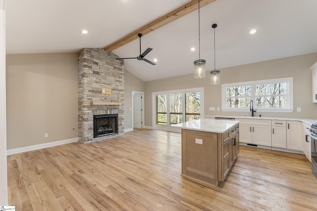 kitchen featuring a center island, pendant lighting, open floor plan, white cabinetry, and light stone countertops