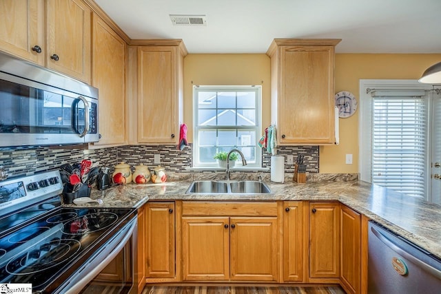 kitchen with appliances with stainless steel finishes, backsplash, hardwood / wood-style flooring, and sink