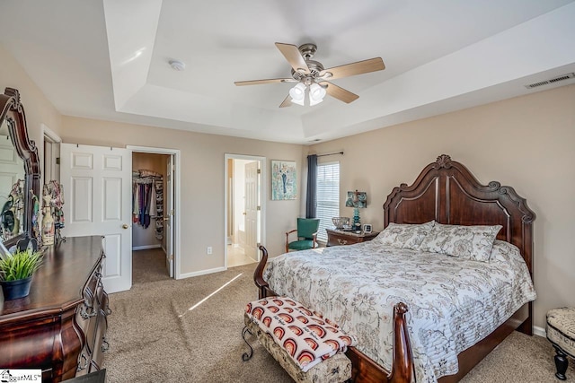 bedroom featuring ceiling fan, light colored carpet, a walk in closet, and a closet