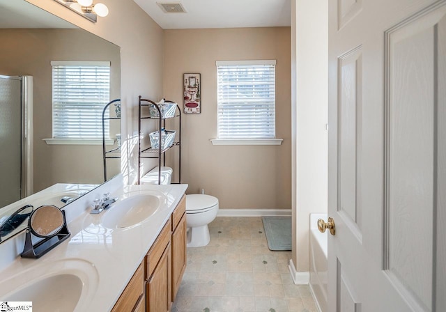 bathroom with vanity, a healthy amount of sunlight, toilet, and a shower with door