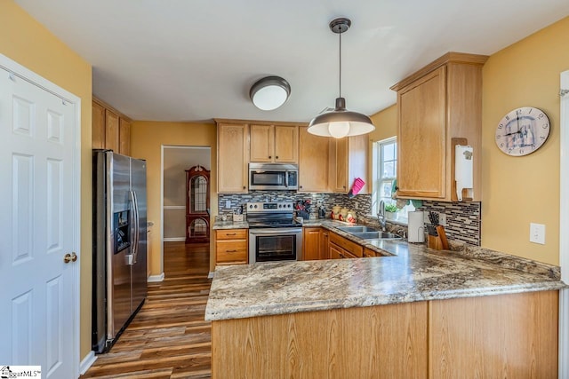 kitchen featuring sink, hanging light fixtures, dark hardwood / wood-style flooring, kitchen peninsula, and appliances with stainless steel finishes