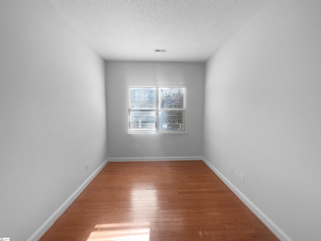 spare room featuring hardwood / wood-style floors and a textured ceiling