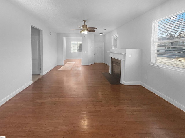 unfurnished living room with ceiling fan, dark hardwood / wood-style flooring, and a textured ceiling