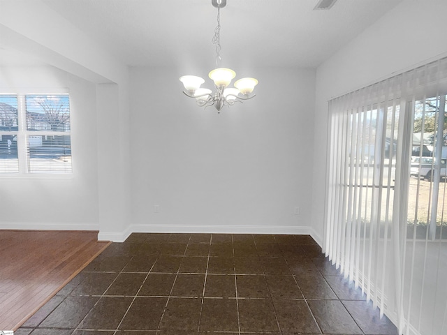 spare room featuring dark hardwood / wood-style flooring, plenty of natural light, and an inviting chandelier