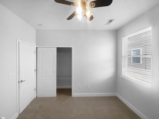 unfurnished bedroom featuring carpet flooring, ceiling fan, a closet, and a textured ceiling