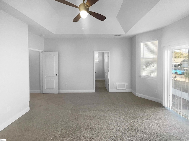 carpeted spare room with ceiling fan and a raised ceiling