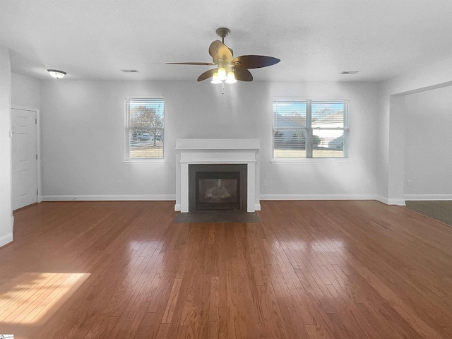 unfurnished living room with ceiling fan, plenty of natural light, and dark hardwood / wood-style floors