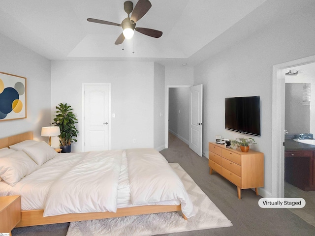 carpeted bedroom featuring ensuite bathroom, a raised ceiling, and ceiling fan