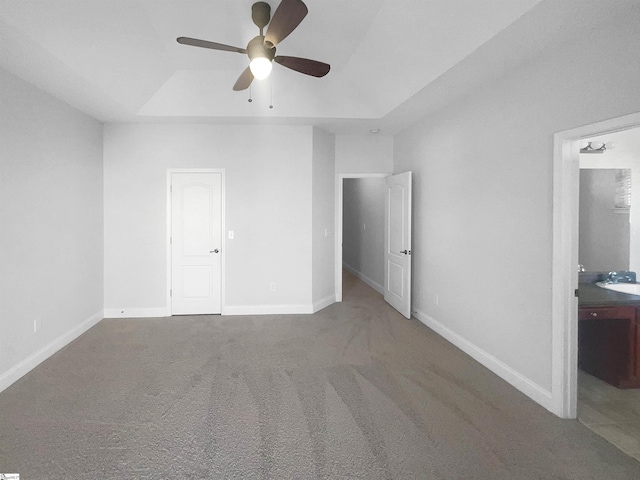 unfurnished bedroom featuring carpet, connected bathroom, a tray ceiling, and ceiling fan