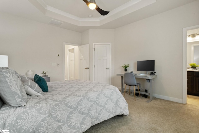 bedroom with ceiling fan, light colored carpet, connected bathroom, and a tray ceiling