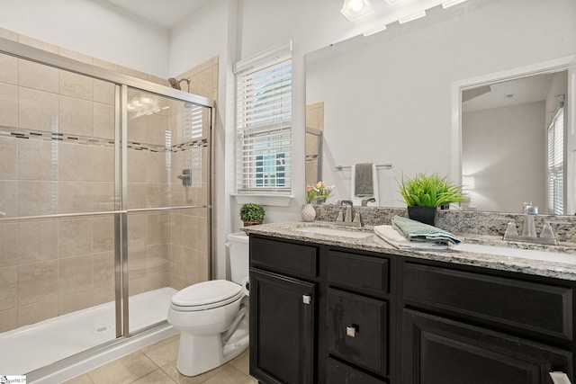 bathroom with tile patterned floors, a shower with door, vanity, and toilet