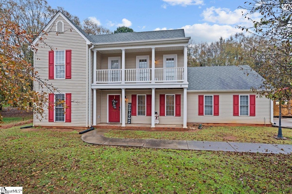 view of front facade with a balcony and a front yard