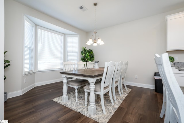 dining space with dark hardwood / wood-style floors, an inviting chandelier, and a wealth of natural light