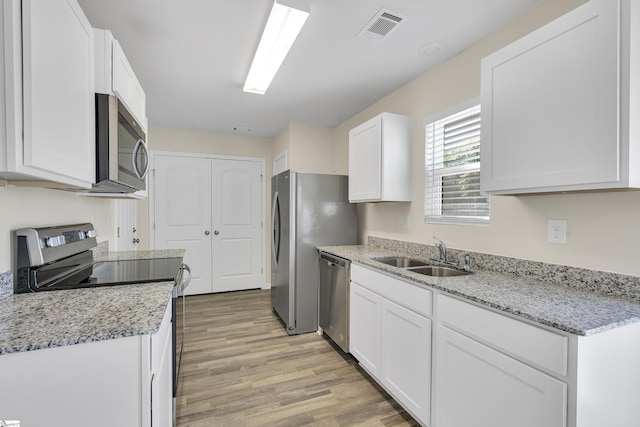 kitchen with sink, white cabinets, light hardwood / wood-style flooring, and appliances with stainless steel finishes