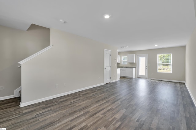 unfurnished living room with dark wood-type flooring