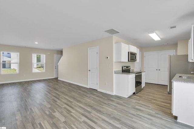 kitchen featuring white cabinets, sink, light hardwood / wood-style flooring, appliances with stainless steel finishes, and light stone counters