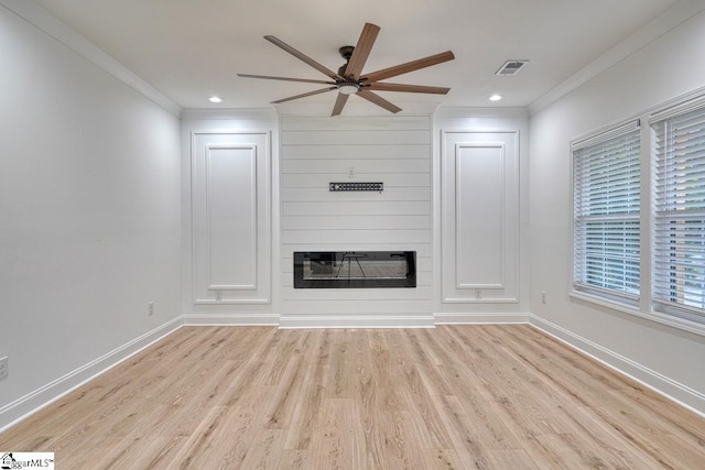 unfurnished living room featuring ceiling fan, a large fireplace, light wood-type flooring, and crown molding