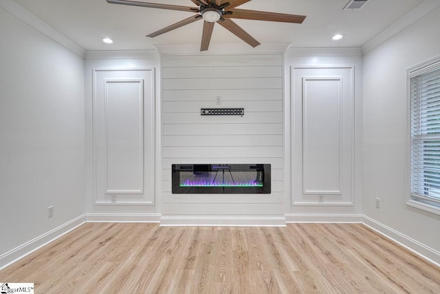 unfurnished living room featuring a large fireplace, light hardwood / wood-style floors, ceiling fan, and ornamental molding