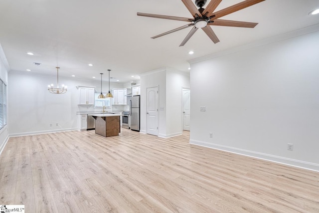 unfurnished living room featuring crown molding, light hardwood / wood-style flooring, ceiling fan with notable chandelier, and sink