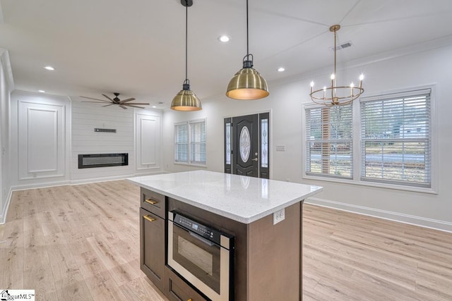 kitchen with light hardwood / wood-style flooring, hanging light fixtures, a kitchen island, and light stone counters