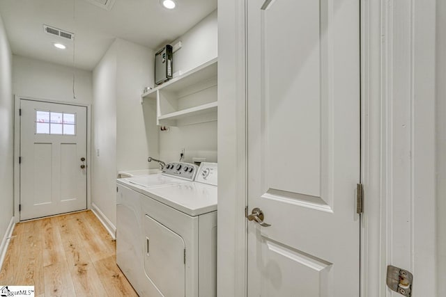 laundry area with light wood-type flooring and washing machine and clothes dryer