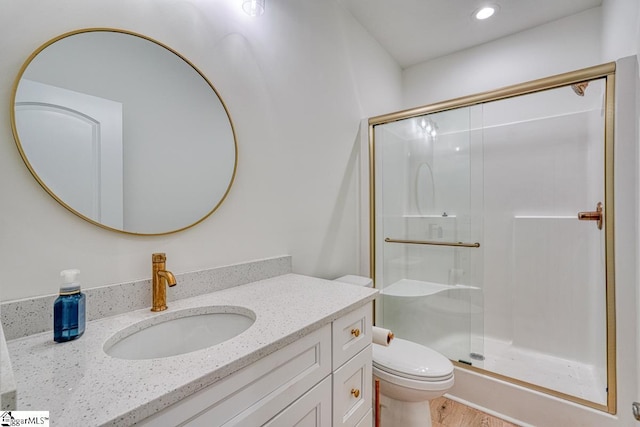 bathroom with hardwood / wood-style flooring, toilet, vanity, and walk in shower