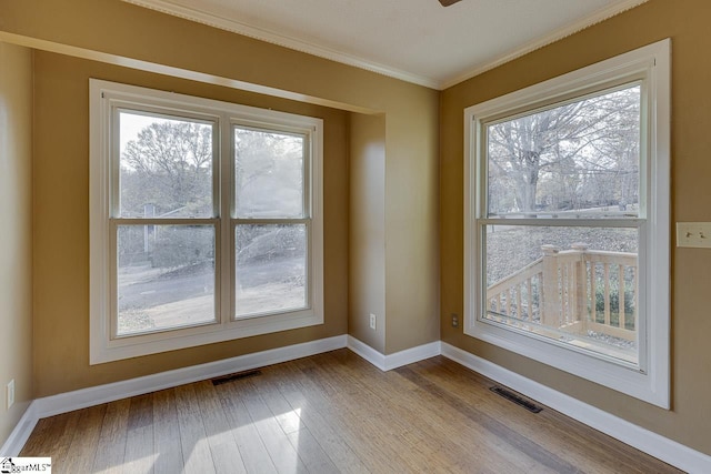 empty room featuring ornamental molding and light hardwood / wood-style flooring