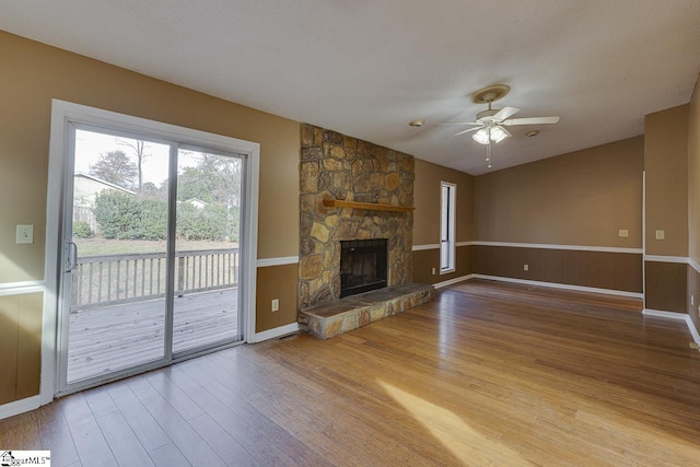 unfurnished living room featuring ceiling fan, a fireplace, light hardwood / wood-style floors, and a textured ceiling