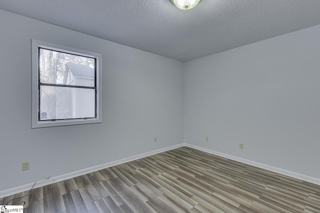 empty room with wood-type flooring and a textured ceiling