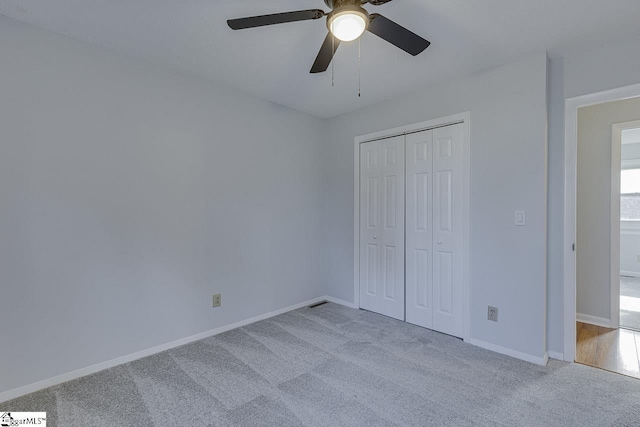 unfurnished bedroom featuring ceiling fan, a closet, and light carpet