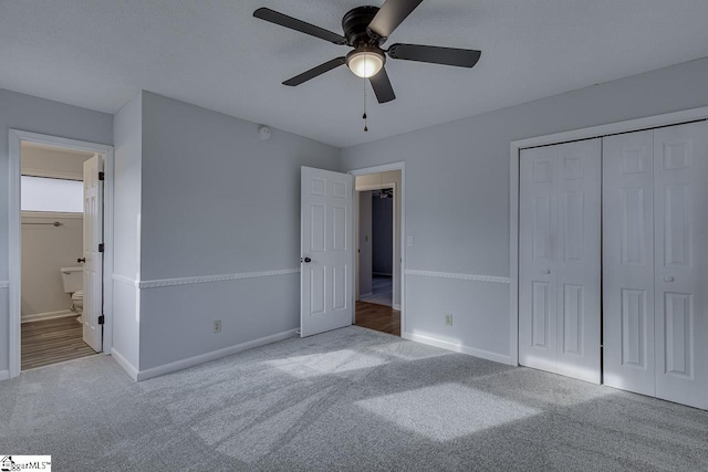 unfurnished bedroom featuring carpet, ensuite bath, a textured ceiling, ceiling fan, and a closet