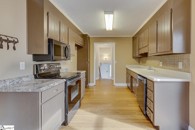 kitchen with appliances with stainless steel finishes, light wood-type flooring, backsplash, ornamental molding, and a textured ceiling