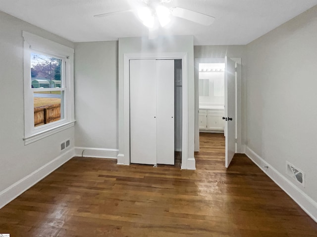 unfurnished bedroom with ensuite bath, ceiling fan, a closet, and dark hardwood / wood-style floors