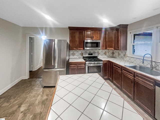 kitchen with tile countertops, sink, appliances with stainless steel finishes, and tasteful backsplash